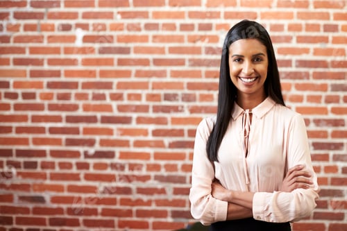 Preview: Portrait Of Smiling Young Businesswoman Standing Against Brick Wall In Modern Office