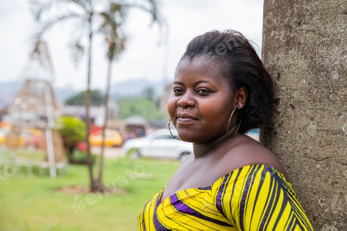 Preview: Portrait of a pensive young African woman leaning against a tree outdoors