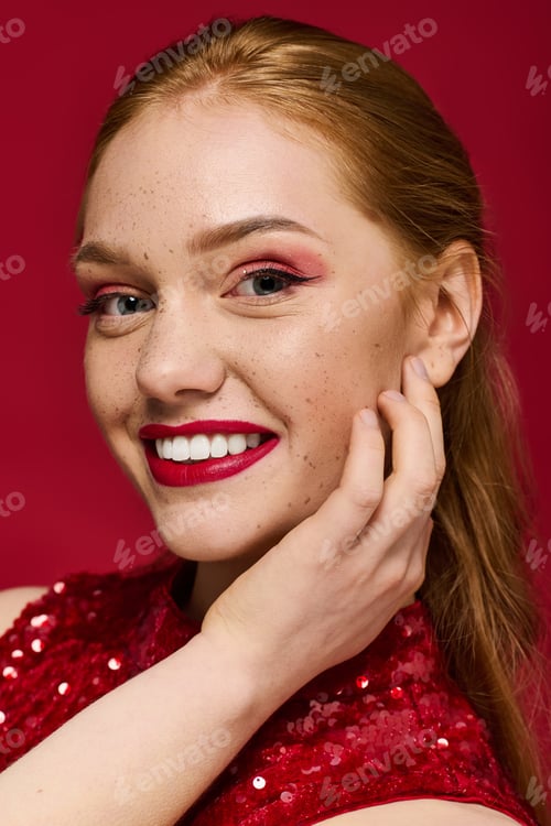 Preview: Young woman with radiant smile posing gracefully against vibrant red backdrop