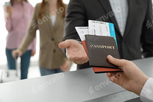 Preview: Agent giving passports and tickets to man at check-in desk in airport, closeup