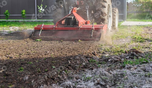 Preview: Tractor cultivating soil in the garden. Selective focus.