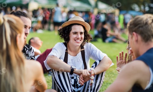 Preview: Group of young friends sitting on ground at summer festival