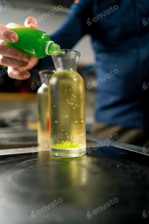 Preview: chef in kitchen experiments by adding multi-colored molecular caviar grains to container with water