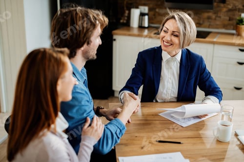 Preview: Happy insurance agent shaking hands with young couple after the meeting.
