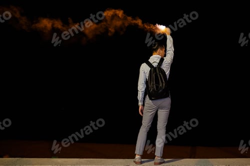 Preview: Back view of man with backpack and flame at night
