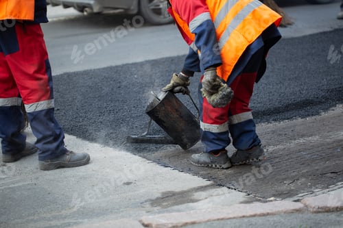 Preview: A worker pours liquid asphalt, molten bitumen from a bucket of resin.