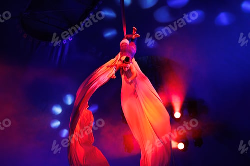 Vista previa: Aerialist performs a dangerous trick on a fabric high under dome of the circus under the spotlight.