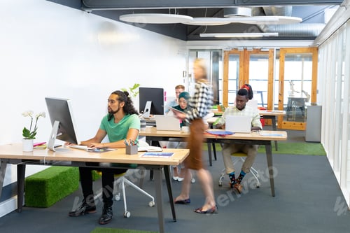 Preview: Front view of diverse business people working at desk in a modern office