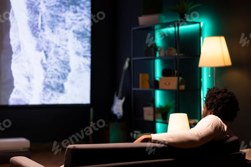 Preview: Person enjoying scenery shots on large television set