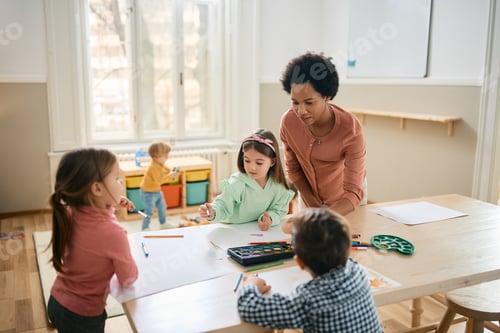 Preview: Group of kids and their black teacher enjoying during art class at kindergarten.