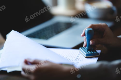 Preview: person's hand stamping with approved stamp on certificate document public paper at desk