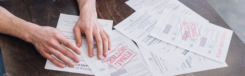 Preview: Cropped view of male hands near documents with foreclosure and final notice lettering on table,