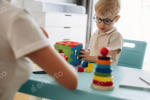 Preview: Composes logic puzzles. Speech therapist is with young boy indoors