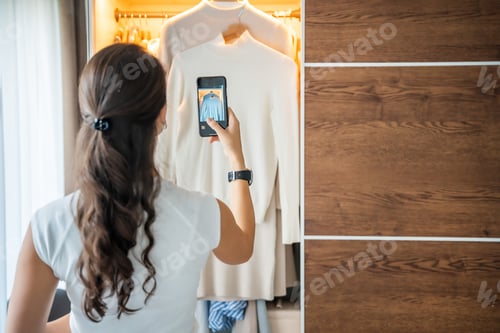 Preview: Young woman taking photos of old unwanted clothes for sale in smartphone app