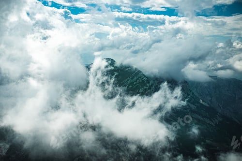 Preview: Stunning aerial view of a mountainous landscape with fluffy white clouds dotting the sky