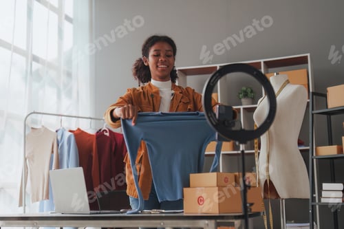 Preview: American African entrepreneur smile and use a smartphone to live stream. Successful SME entrepreneur