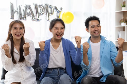 Preview: Group of friends cheering for a ball while watching television at a birthday party at home.