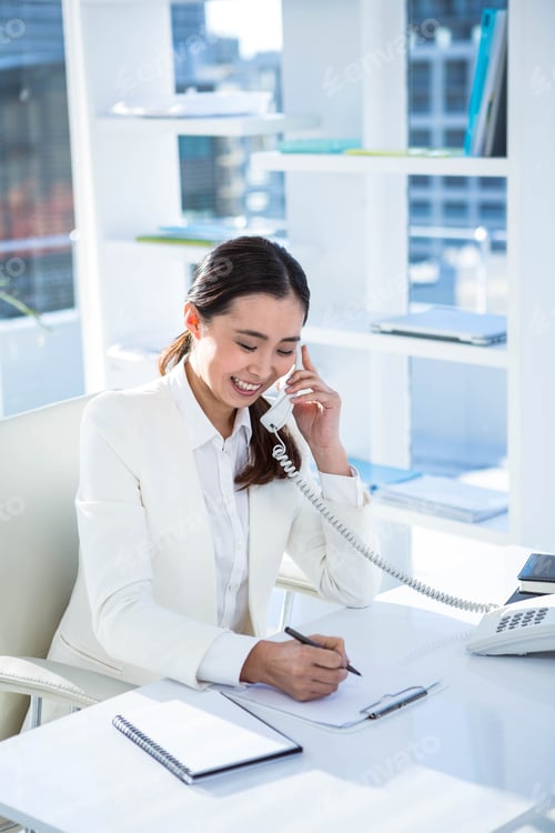 Preview: Smiling businesswoman on her telephone at the desk in work