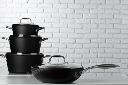 Preview: Black kitchenware on table against white brick wall