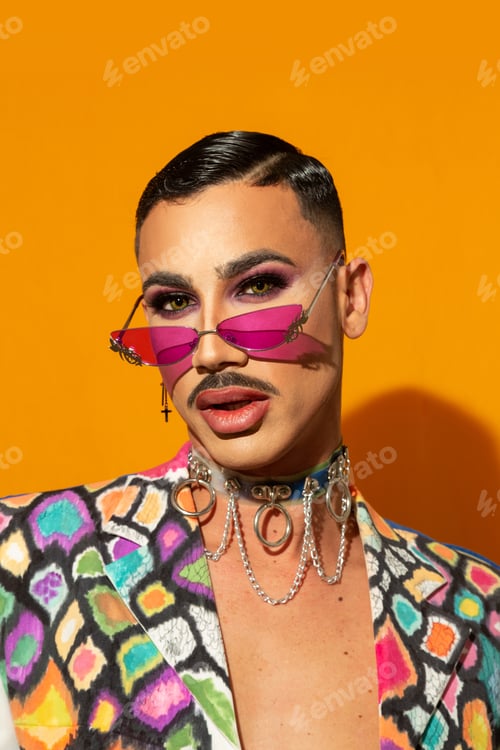 Preview: Portrait of a young drag queen in colorful dress on yellow background