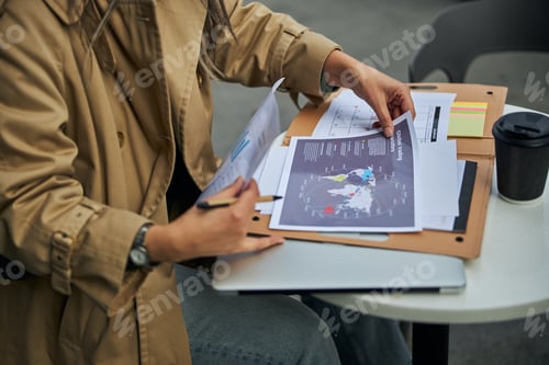 Preview: Businesswoman working with papers in outdoor cafe