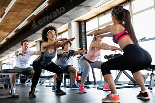 Preview: Multiethnic group of people training in a gym. Trainer and sportive fit persons exercising