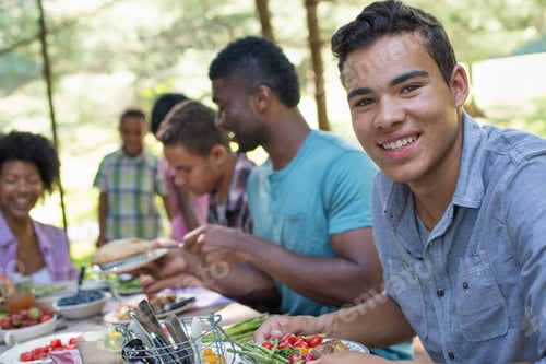 Preview: A family picnic meal in the shade of tall trees,parents and children enjoying a meal