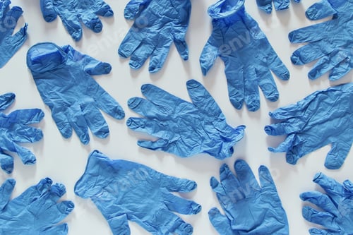 Many Blue Medical Gloves Scattered on a White Surface