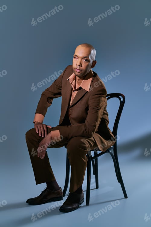 Preview: bold african american man with myasthenia gravis syndrome sitting on chair and looking at camera on