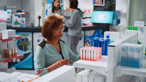 Preview: Female customer analyzing boxes of cardiology drugs