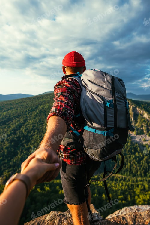 Preview: Portrait of a man holding his woman's hand while walking along a mountain range, vertical photo