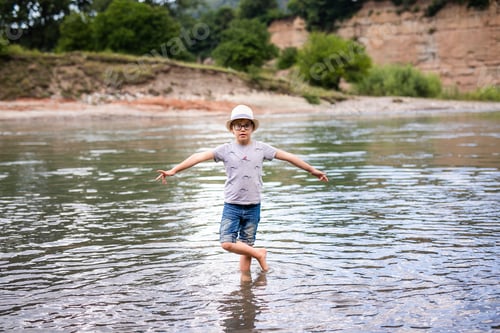 Preview: Little boy in the hat standing into the river