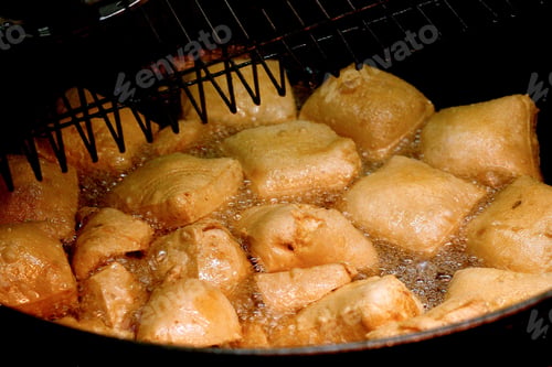 Preview: Close-up of golden brown stinky tofu frying in hot oil in a deep fryer.