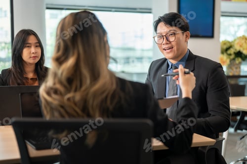 Preview: Back view of businesswoman holding clipboard and pen showing a document during a meeting in office.
