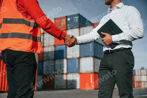 Preview: Making handshake. Two male workers is on the location with containers