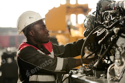 Preview: Side view of young male engineer in workwear repairing indistrial machine