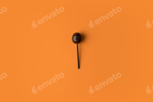 Preview: top view of black sweet halloween lollipop on orange
