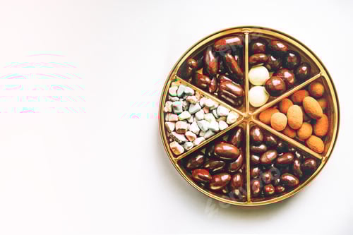 Preview: A set of multicolored chocolates in a round package divided into six sectors on a white background.