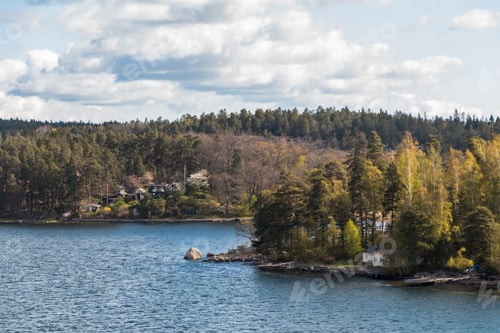 Preview: view from the ship to the rocky coast of Sweden. typical swedish houses on the rocks. cloudy sky