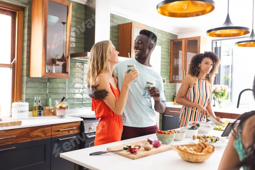 Preview: Young Caucasian woman in an orange dress laughs with a young African American man holding a drink
