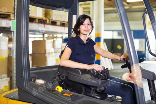Preview: Portrait of female forklift truck driver working in distribution warehouse