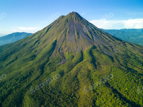 Preview: Scenic aerial view of Arenal Volcano in Costa Rica with lush green vegetation and clear blue sky
