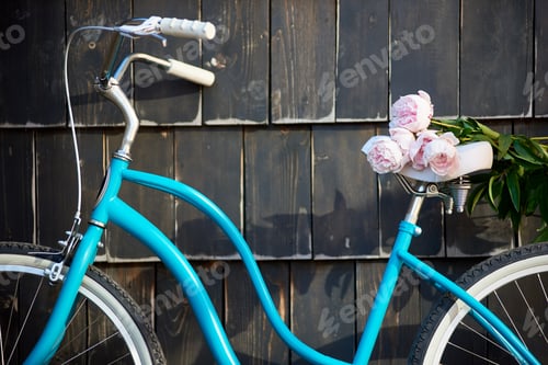 Preview: Close-up blue vintage bicycle on which lies bouquet pink peonies