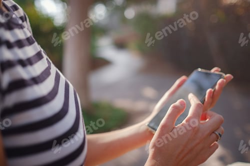 Preview: A woman wearing a protective mask looks at her smartphone display