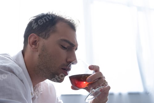 Preview: depressed man in shirt drinking cognac at home