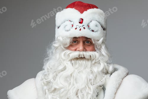 Preview: Father Frost in winter hat with white beard looking at camera.