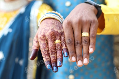 Preview: Closeup shot of an Indian newly-wed couple's hands with rings