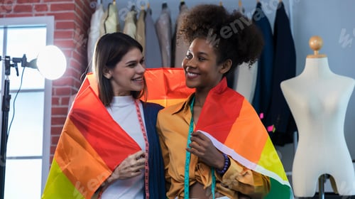 Preview: Happy women standing with a pride rainbow flag.