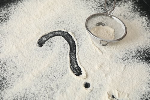 Preview: Flour, sieve and question mark on black background