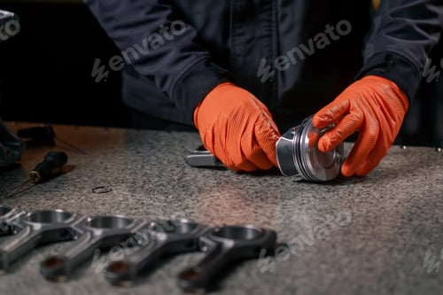 Preview: close-up At a service station on the table young engine repairman assembles a new piston part